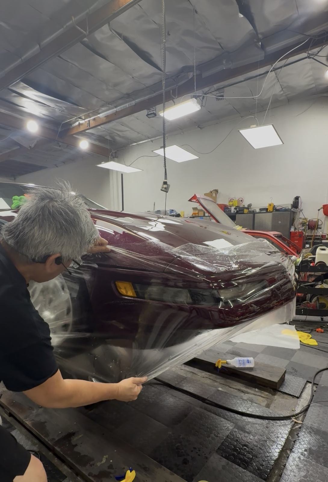 Richard applying PPF film to the front of a burgundy Corvette